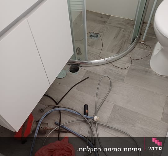 צינורות וכלי עבודה על רצפת חדר אמבטיה